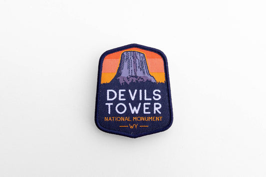 Laid flat on white, the Devils Tower National Monument patch shows its striped orange sky and navy border.