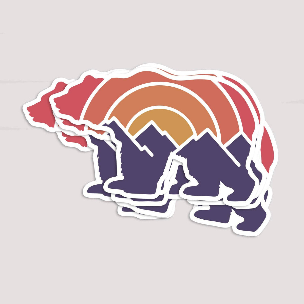 Several Adventure Grizzly Bear stickers fan out in a loose stack on a pale grey surface.