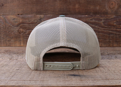 Rear of the Shenandoah National Park trucker hat, khaki mesh and open snap closure over rough brown planks.