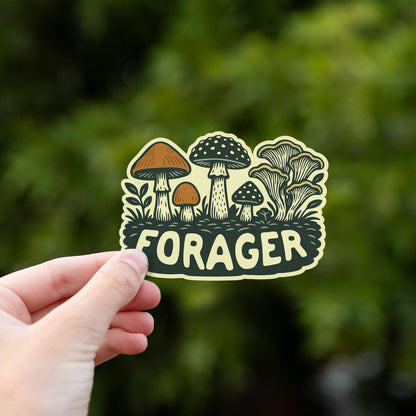 Fingers grip the lower edge of the Forager Mushrooms sticker with a green tree canopy behind.