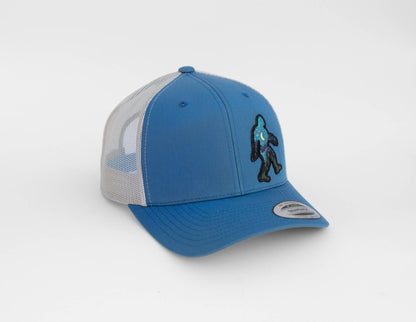 Blue and white Bigfoot Night Sky trucker hat seen from the side, patch stitched on the blue front panel.