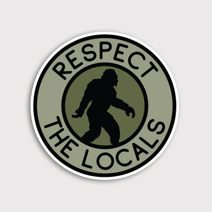 Round olive Bigfoot Respect The Locals sticker on a plain grey background, black silhouette mid stride.