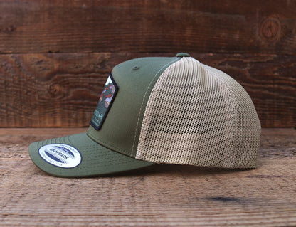 Side profile on wood boards, the Shenandoah National Park trucker hat pairs an olive crown with khaki mesh.
