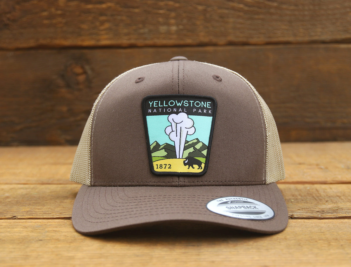 Warm brown crown on the Yellowstone National Park trucker hat, photographed head on over pine planks.