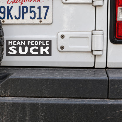 Below a California plate on a white Jeep's tailgate, the black Mean People Suck sticker sits beside the door hinge.