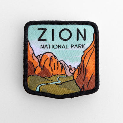 Up close, the Zion National Park patch fills the frame with orange cliffs, green flats and a pale blue sky.