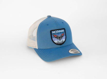 Blue crown and cream mesh pair up on the Mothman trucker hat, patch bright against the lighter panel.