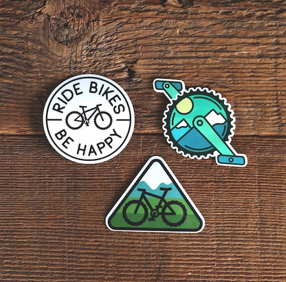 Stacked on weathered planks, the MTB sticker set spreads out with the trail triangle below the crank decal.