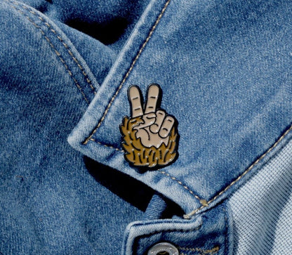 Fastened through the collar of a faded denim jacket, the Bigfoot Peace Pin catches the stitching lines.