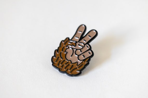 Close and slightly tilted, the Bigfoot Peace Pin glosses under soft light on a white surface.