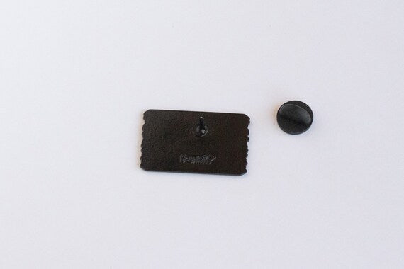 Reverse of the Welcome to Colorful Colorado pin, shot closer so the stamped mark and black clutch stand out.