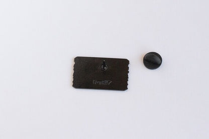 Reverse of the Welcome to Colorful Colorado pin, shot closer so the stamped mark and black clutch stand out.
