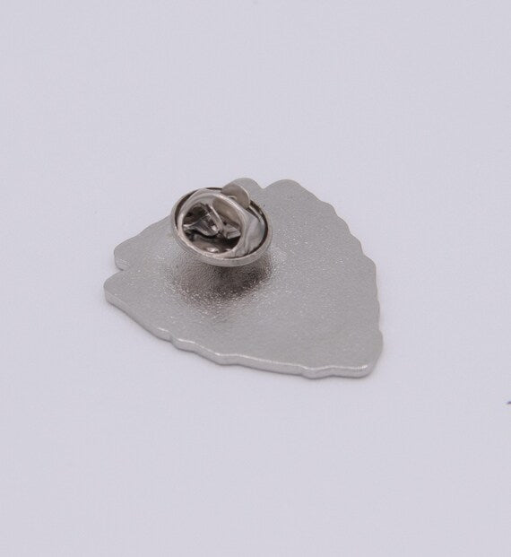 Tilted closer to the camera, the Leave No Trace pin shows its brushed metal back and round clutch.