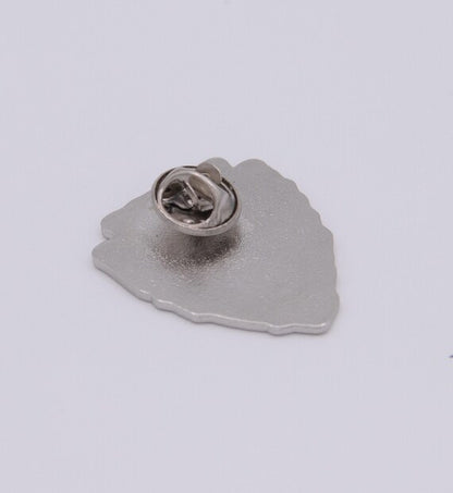 Tilted closer to the camera, the Leave No Trace pin shows its brushed metal back and round clutch.