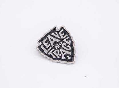 Straight on and centered, the Leave No Trace enamel pin sits flat with crisp white letters on black.