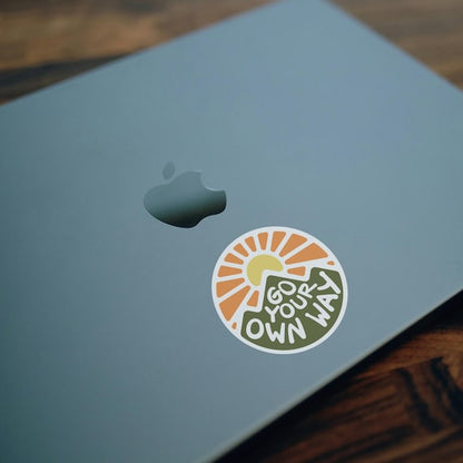 On the lid of a blue laptop, the Go Your Own Way sticker sits just below the apple logo.